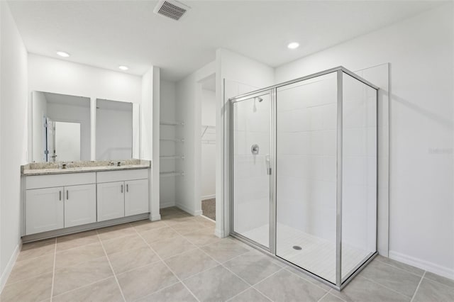 full bathroom with visible vents, tile patterned floors, a sink, a stall shower, and a spacious closet