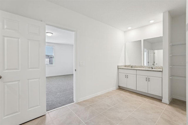 full bath featuring baseboards, double vanity, a sink, and tile patterned flooring