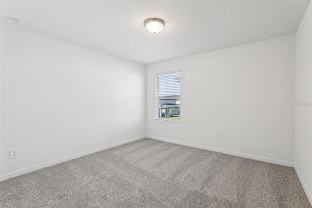 carpeted empty room with baseboards and a textured ceiling