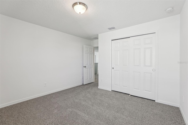 unfurnished bedroom featuring carpet flooring, a textured ceiling, a closet, and visible vents