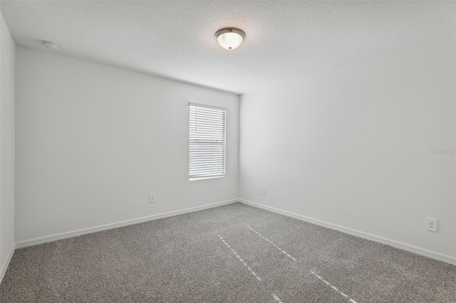 unfurnished room featuring baseboards, a textured ceiling, and carpet