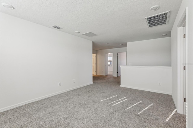 spare room with carpet floors, a textured ceiling, and visible vents