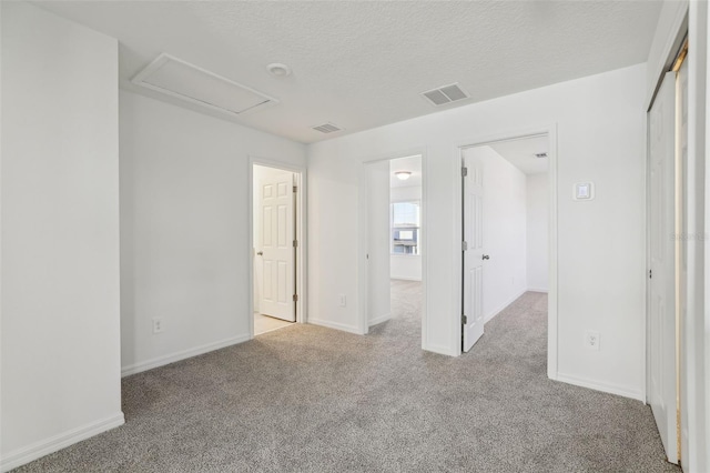 carpeted empty room with baseboards, a textured ceiling, and visible vents