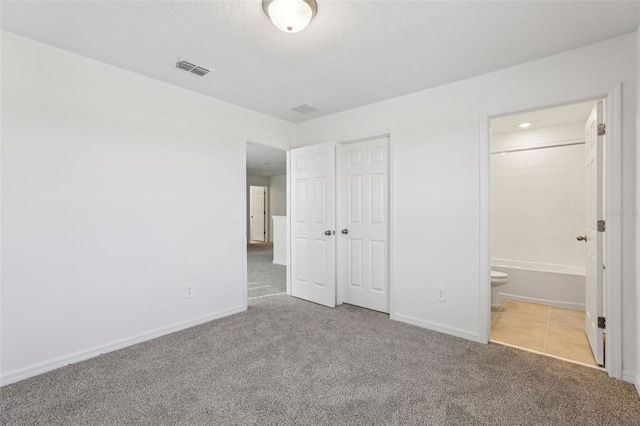 unfurnished bedroom with carpet flooring, baseboards, ensuite bath, and visible vents