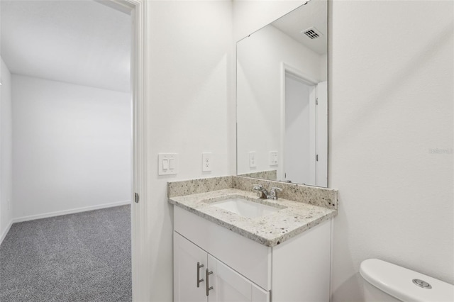 half bath featuring baseboards, visible vents, toilet, and vanity
