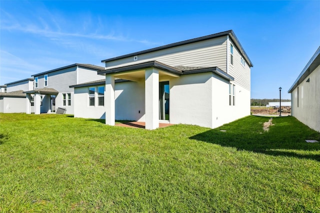back of property featuring stucco siding and a lawn