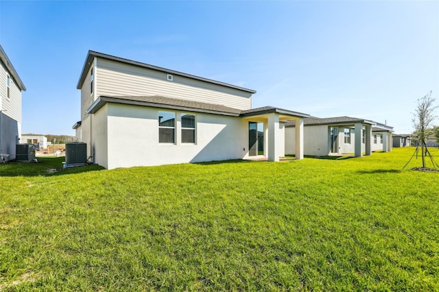 back of property with a lawn, cooling unit, and stucco siding