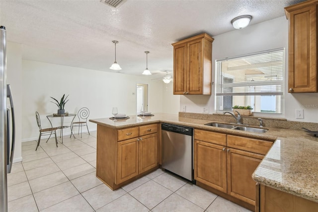 kitchen featuring light tile patterned floors, a peninsula, a sink, appliances with stainless steel finishes, and brown cabinetry