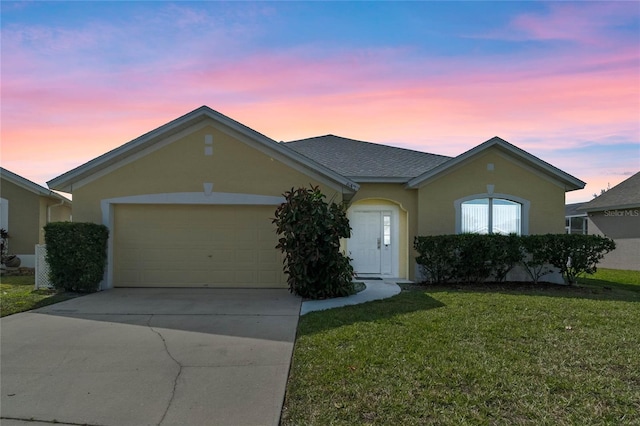 ranch-style home featuring an attached garage, driveway, a front lawn, and stucco siding