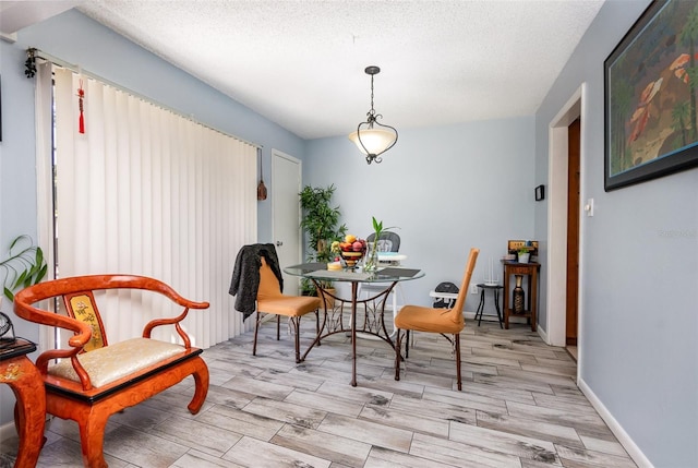 dining room featuring wood tiled floor, baseboards, and a textured ceiling