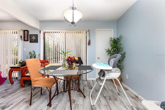 dining area with light wood-style flooring, baseboards, and a textured ceiling