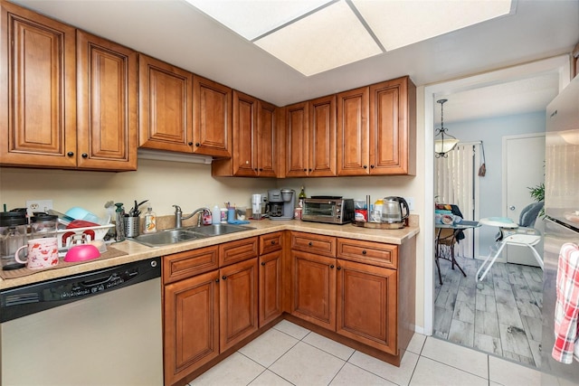 kitchen with dishwasher, brown cabinetry, and a sink