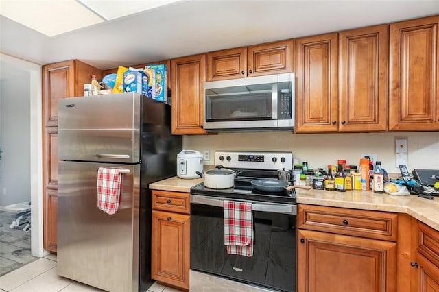 kitchen with appliances with stainless steel finishes, brown cabinets, and light countertops