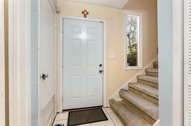 entrance foyer with light tile patterned flooring, visible vents, and stairs