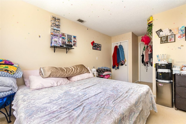 bedroom with light carpet, a closet, a textured ceiling, and visible vents