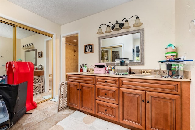 full bathroom featuring a textured ceiling, vanity, and tile patterned floors