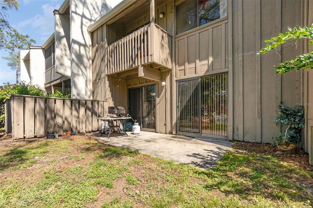 back of house featuring a balcony, a patio area, and board and batten siding