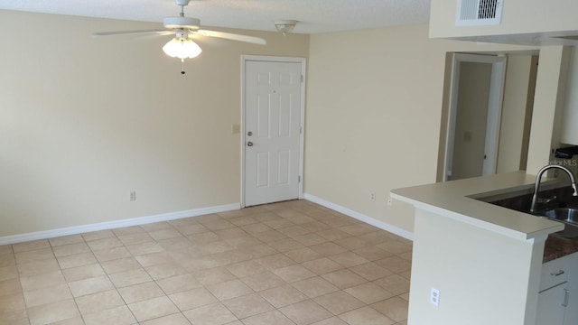 unfurnished dining area featuring visible vents, a ceiling fan, a sink, a textured ceiling, and baseboards