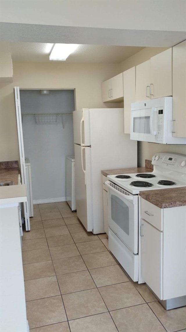 kitchen featuring white appliances, white cabinetry, and light tile patterned flooring