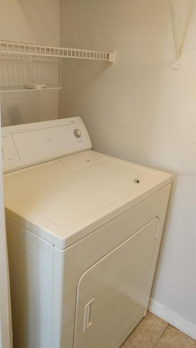 laundry room with laundry area, baseboards, washer / clothes dryer, and light tile patterned flooring