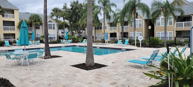 community pool featuring a patio area, fence, and a residential view