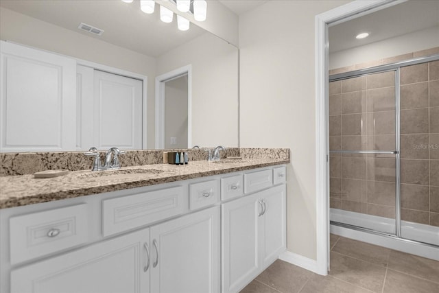 bathroom with tile patterned flooring, visible vents, a sink, and a shower stall