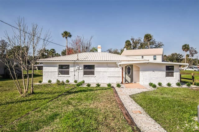 single story home featuring metal roof, a front lawn, and stucco siding