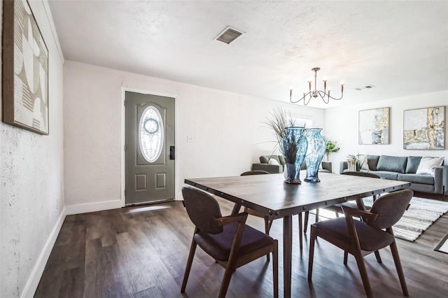 dining area with baseboards, visible vents, a textured wall, dark wood-style flooring, and an inviting chandelier