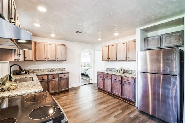 kitchen with dark wood-style flooring, freestanding refrigerator, a sink, range with electric cooktop, and under cabinet range hood