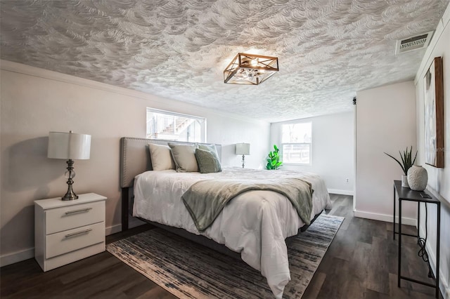 bedroom featuring visible vents, dark wood finished floors, a textured ceiling, and baseboards