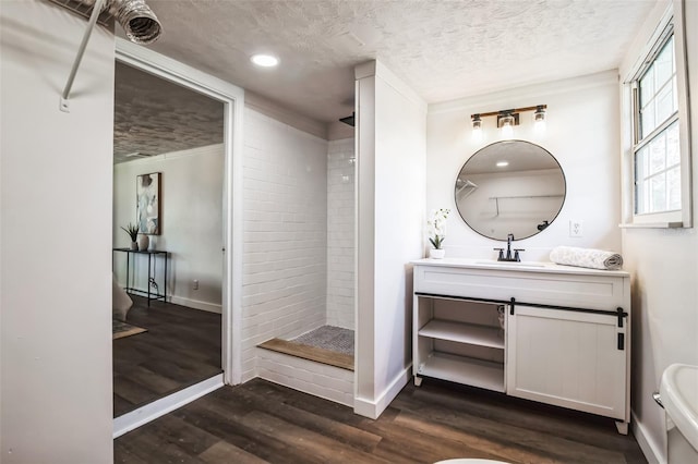 bathroom with a stall shower, baseboards, wood finished floors, a textured ceiling, and vanity