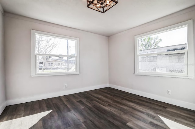 unfurnished room featuring dark wood-type flooring, a chandelier, a healthy amount of sunlight, and baseboards