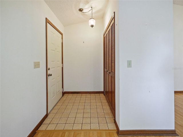 hallway featuring a textured ceiling and baseboards