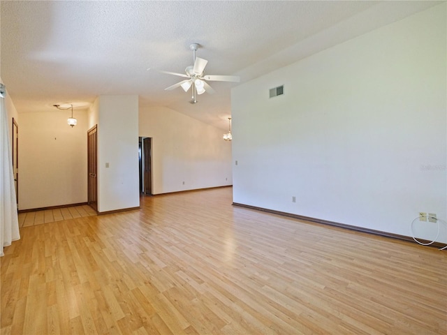 unfurnished room featuring visible vents, lofted ceiling, ceiling fan, a textured ceiling, and light wood-type flooring