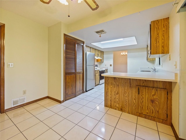 kitchen featuring freestanding refrigerator, visible vents, a sink, and white range with electric stovetop