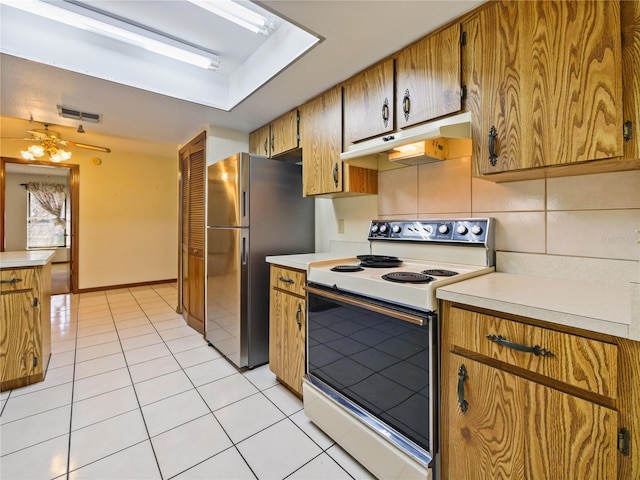 kitchen featuring light tile patterned flooring, under cabinet range hood, white electric range, light countertops, and freestanding refrigerator