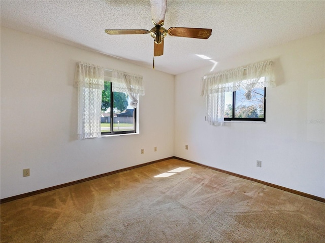 carpeted spare room featuring a ceiling fan, a textured ceiling, and baseboards