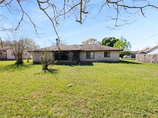 back of property featuring a yard, fence, a sunroom, and stucco siding