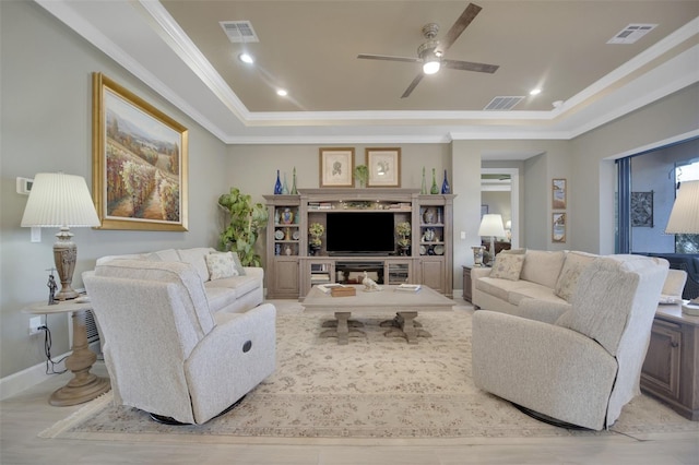 living area with a raised ceiling, visible vents, and crown molding