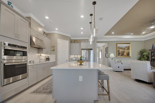 kitchen with decorative backsplash, open floor plan, light countertops, stainless steel appliances, and under cabinet range hood