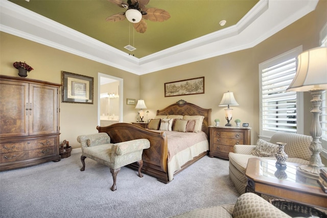 bedroom featuring a raised ceiling, light colored carpet, visible vents, ensuite bathroom, and ornamental molding