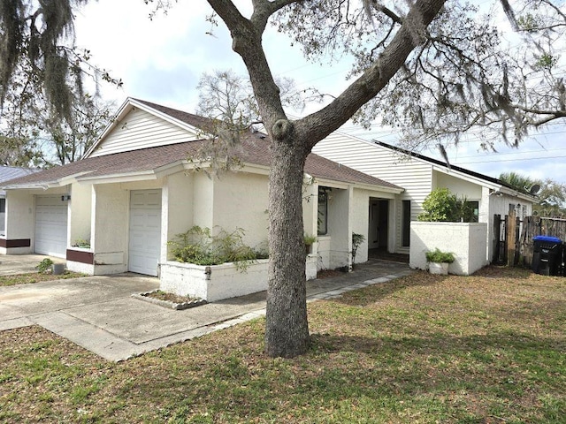 view of front of house with a shingled roof, an attached garage, fence, driveway, and a front lawn