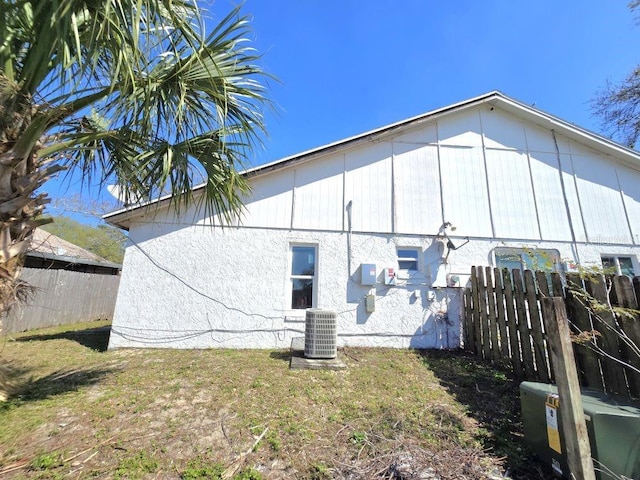 rear view of property featuring a lawn, cooling unit, and fence