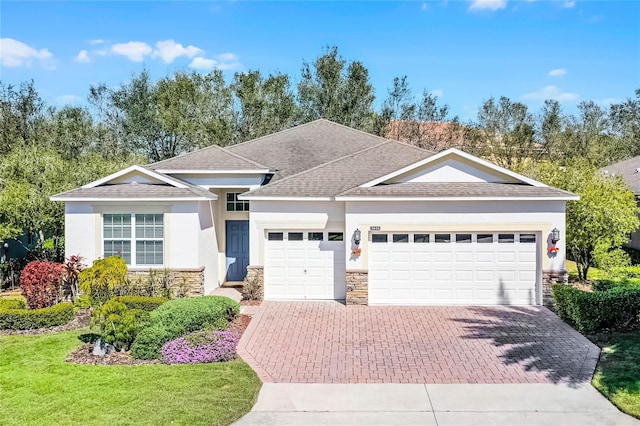 view of front of property featuring a garage, stone siding, decorative driveway, stucco siding, and a front lawn