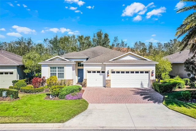 ranch-style house featuring decorative driveway, stucco siding, a garage, stone siding, and a front lawn