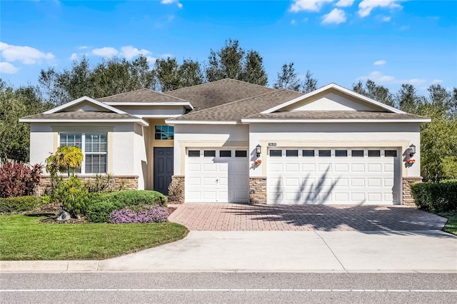 single story home with decorative driveway, stucco siding, a shingled roof, a garage, and stone siding