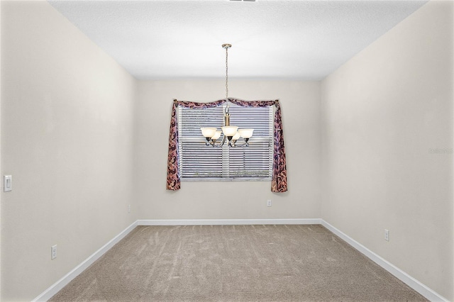 spare room featuring an inviting chandelier, carpet, and baseboards