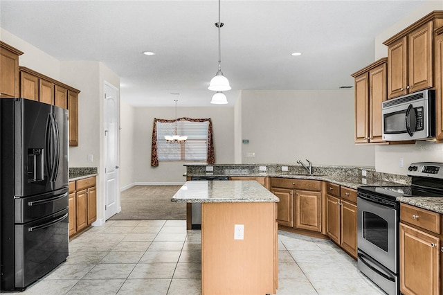 kitchen featuring stainless steel appliances, hanging light fixtures, brown cabinetry, a sink, and a peninsula