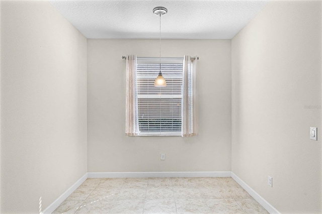 unfurnished room with a textured ceiling and baseboards