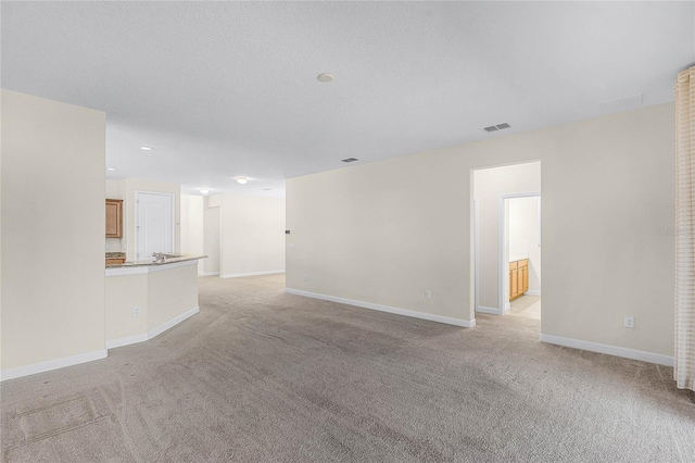 unfurnished living room with light carpet, visible vents, and baseboards